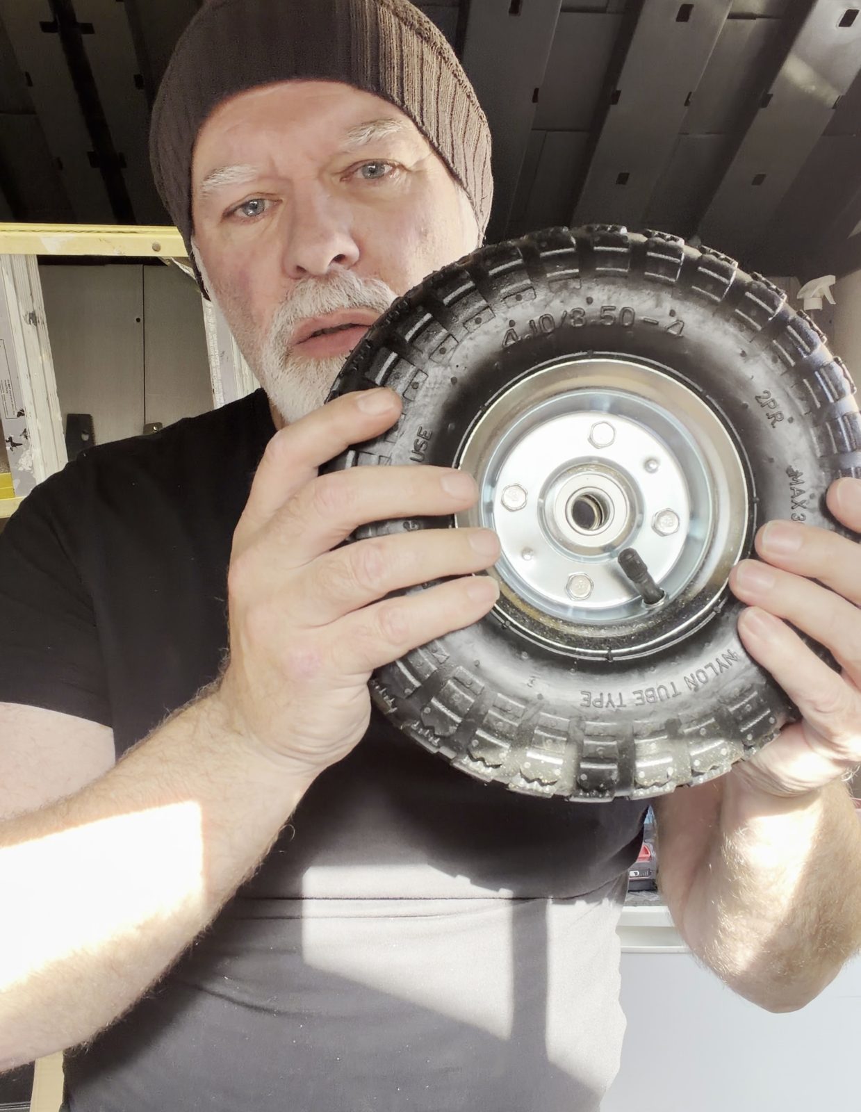 Brett in the shed holding one of Prototype 01's chunky wheels